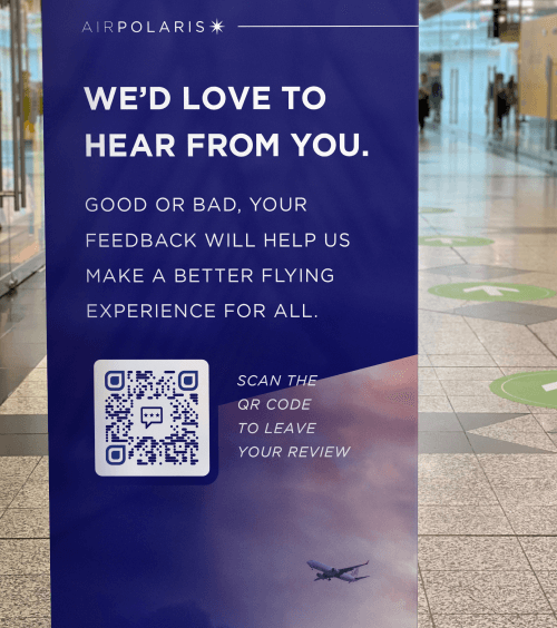 QR Code auf dem Banner einer Airline, der zum Scannen auffordert, um eine Flug-Bewertung abzugeben.