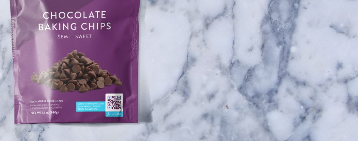 Eine violette Verpackung eines Haselnussriegels aus dunkler Schokolade mit einem aufgedruckten QR Code.