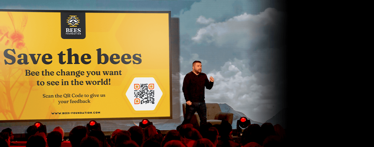 Ein Mitarbeiter der fiktiven Non-Profit-Marke „Bees Foundation“ fordert ein Publikum zum Scannen des QR-Code-Bilds auf.