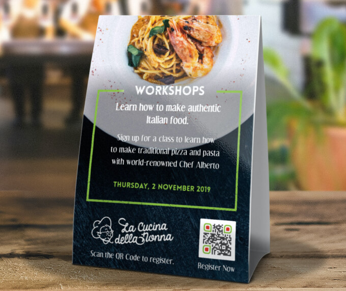 Tischaufsteller eines Restaurants mit einem QR Code, der auf eine Event-Anmeldeseite verlinkt.