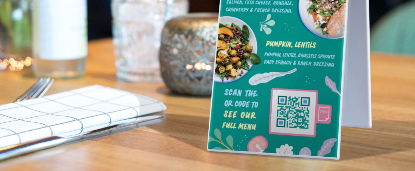Tischaufsteller eines Restaurants mit einem QR Code, der die Speisekarte im PDF-Format anzeigt.