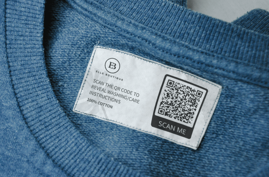 Ein Etikett am Kragen eines blauen Shirts mit einem 2D Barcode, der Wasch- und Pflegeanweisungen verlinkt.