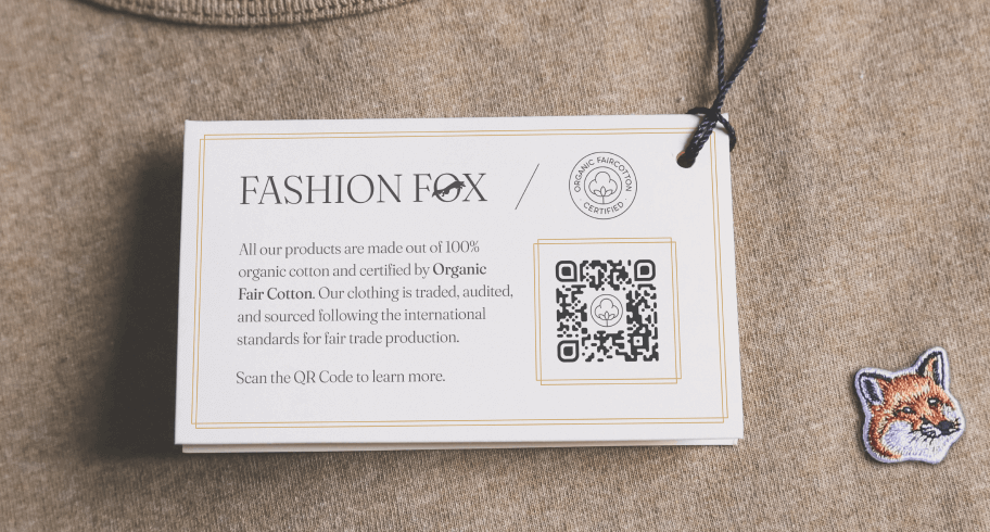 Ein beiger Pullover mit einem Fuchs-Logo und einem weißen Etikett mit einem 2D Barcode.