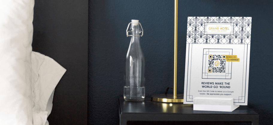 Nachttisch mit einer leeren Wasserflasche, einer Lampe und einem Tisch-Display mit einem Google Bewertung-QR Code für ein Hotel.