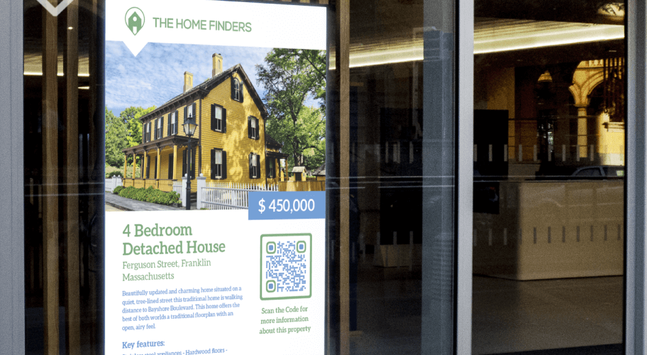 Display in einem Fenster, das ein Haus zum Kauf bewirbt. Ein QR Code bietet Interessierten weitere Informationen.